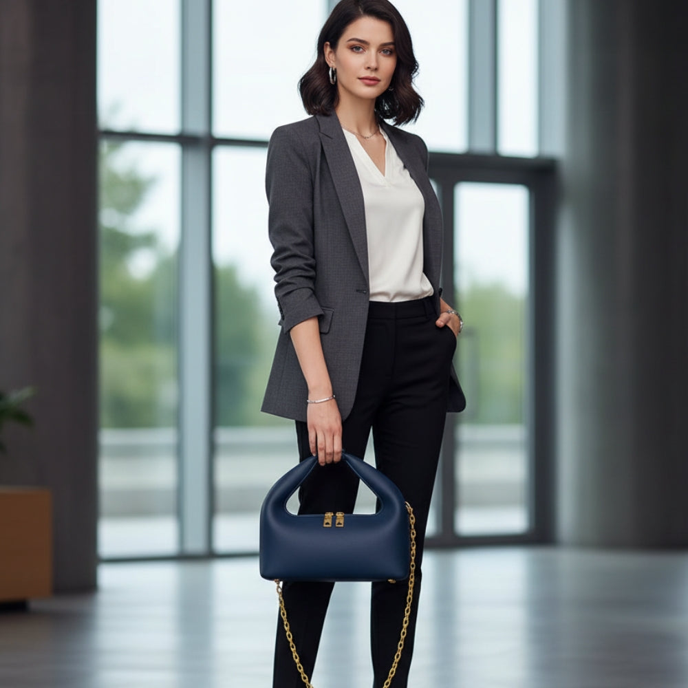 Woman in professional attire holding a navy handbag in an office setting