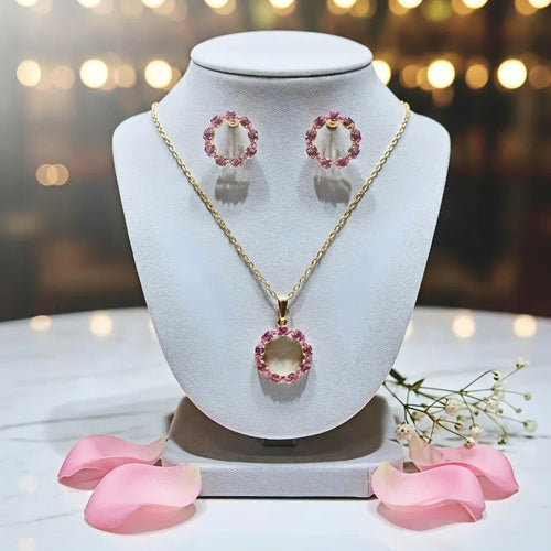 Jewelry set with necklace, earrings, and pink heart-shaped pendants on a white stand with a blurred background.