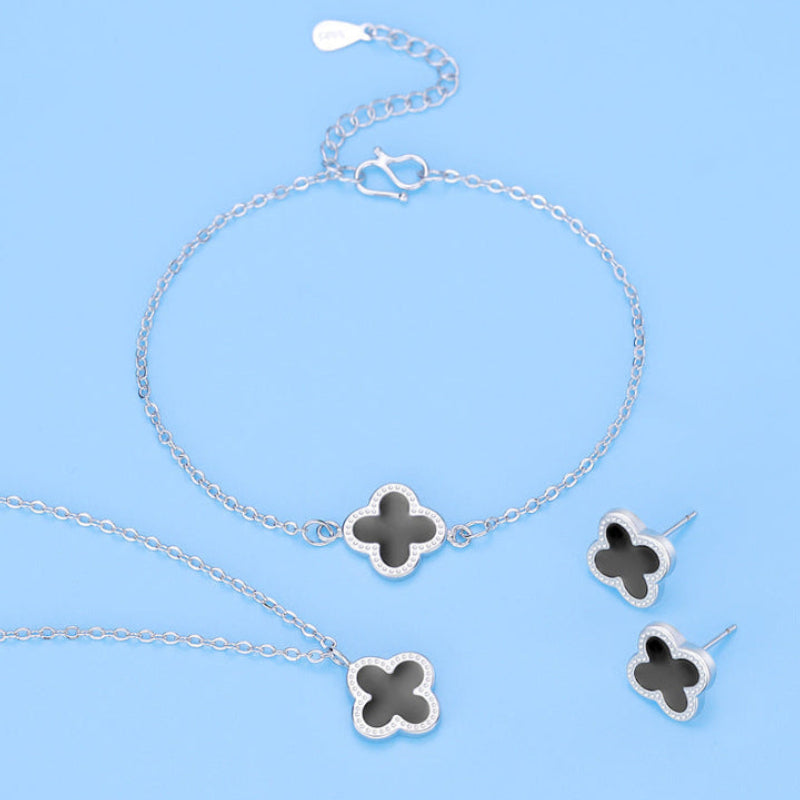 Silver jewelry set with clover-shaped pendants on a blue background
