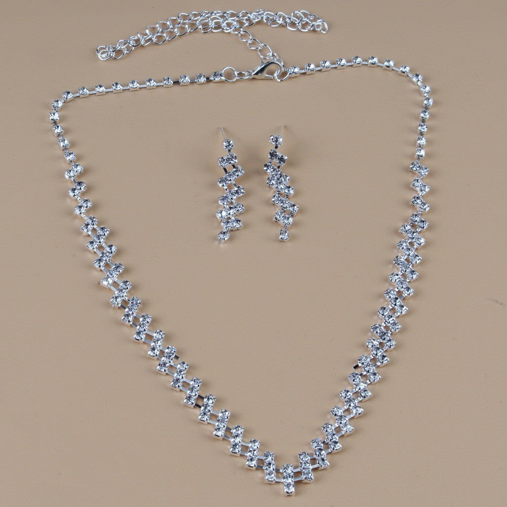Silver necklace and earrings set on a beige background