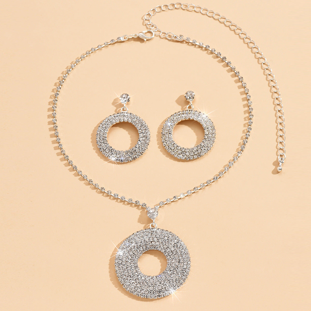 Silver necklace and earrings set on a beige background
